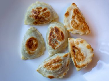 Beyaz tabakta pişmiş sıcak pierojiler yemeye hazır. Pierogi vejetaryen ya da et ya da peynir hazırlayabilir.