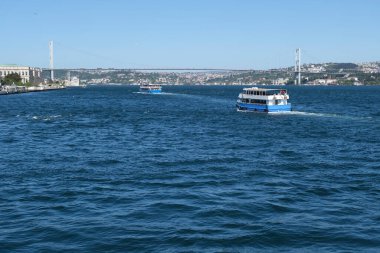 Boğazdaki köprünün önünde feribotla seyahat et. Mavi gökyüzü ve mavi deniz