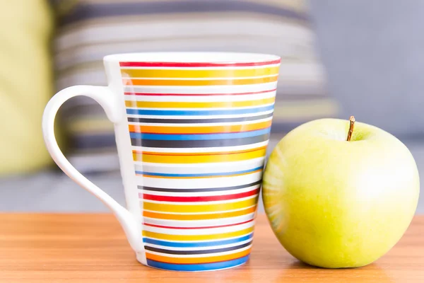 Puchar i jabłko na drewnianym stole — Zdjęcie stockowe