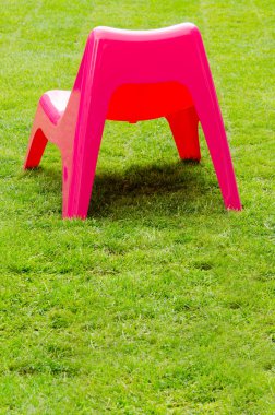 Yeşil çimenlerin üzerinde kırmızı plastik sandalye