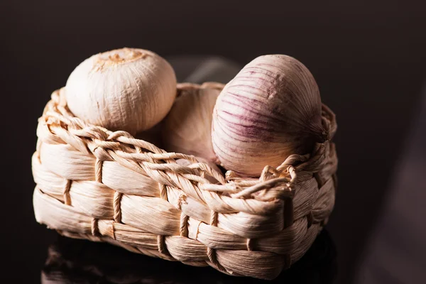 Ein Korb Knoblauch auf dunklem Hintergrund — Stockfoto