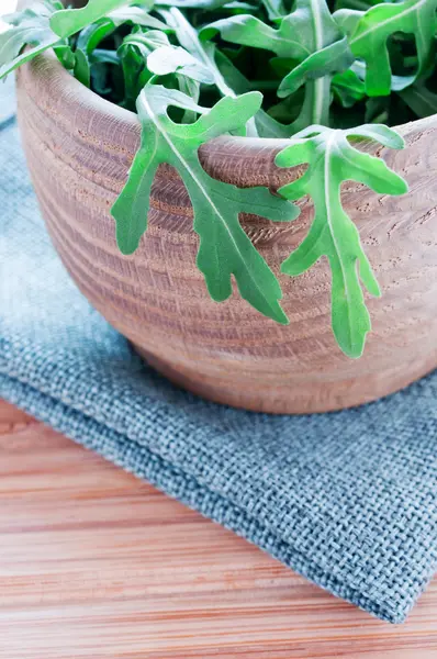 Fresh rucola in wooden plate on table — Stock Photo, Image