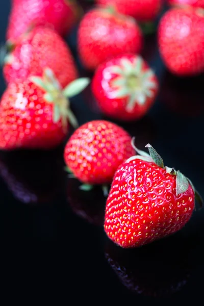 Strawberries on black glass — Stock Photo, Image