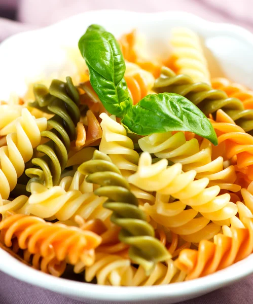 Spiral pasta in bowl with basil — Stock Photo, Image