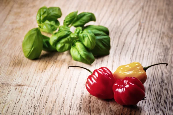 Mix of peppers and basil on wooden table — Stock Photo, Image