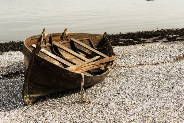 Drewnianą łodzią na kamienistej plaży — Zdjęcie stockowe