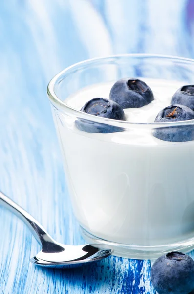 Yogurt ai mirtilli in un bicchiere su blu — Foto Stock