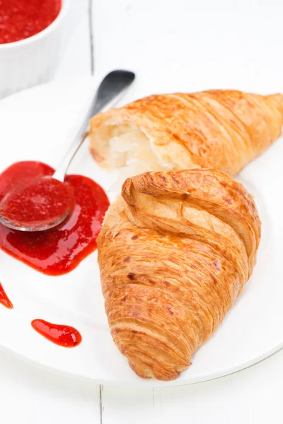 Croissant und Erdbeermarmelade und Löffel — Stockfoto