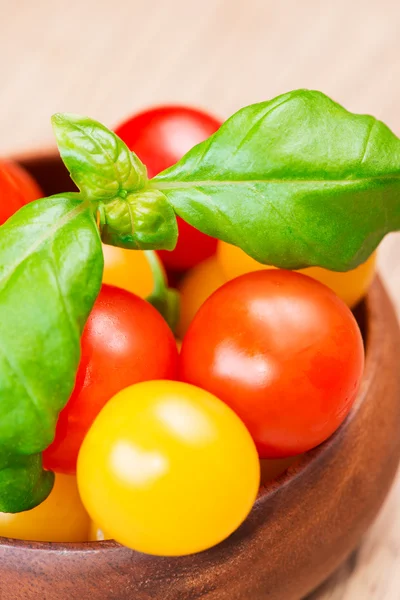 Basil leafs with cherry tomatoes in wooden bowl close up — Stock Photo, Image