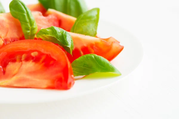 Fresh tomatoes with basil leaves in a plate — Stock Photo, Image