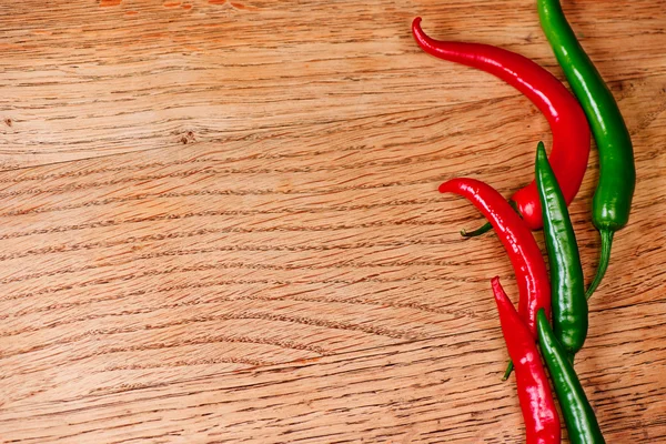 Färsk röd och grön chili paprika på träbord — Stockfoto