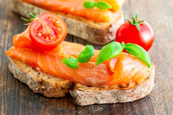 Two salmon sandwiches on wooden table — Stock Photo, Image