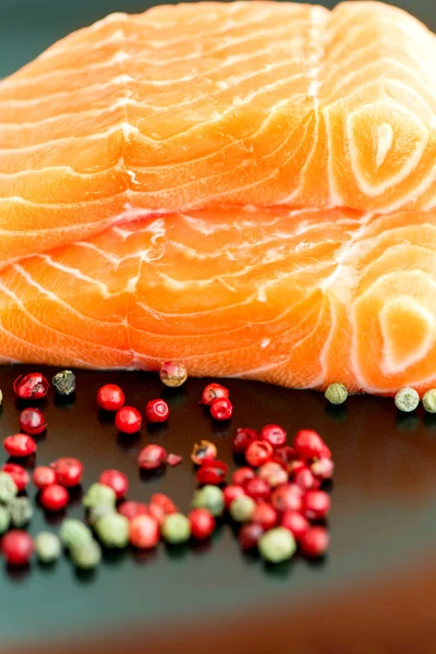 Raw salmon ready to cook close up on black surface — Stock Photo, Image