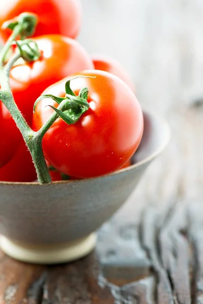 Tomatoes in a bowl on old wooden table vertical side — Stock Photo, Image