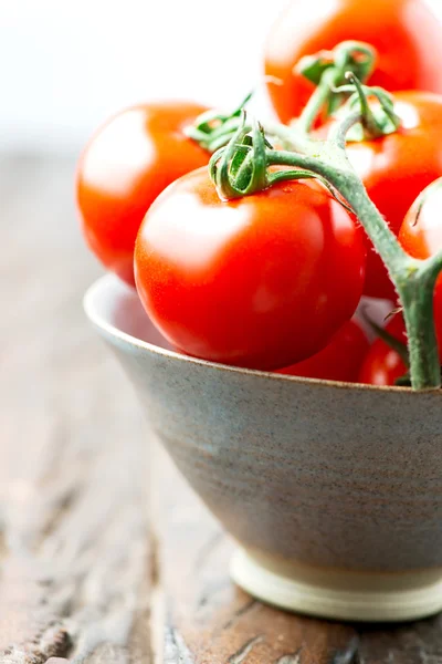 Los tomates en un tazón en la mesa de madera vieja vertical de cerca — Foto de Stock