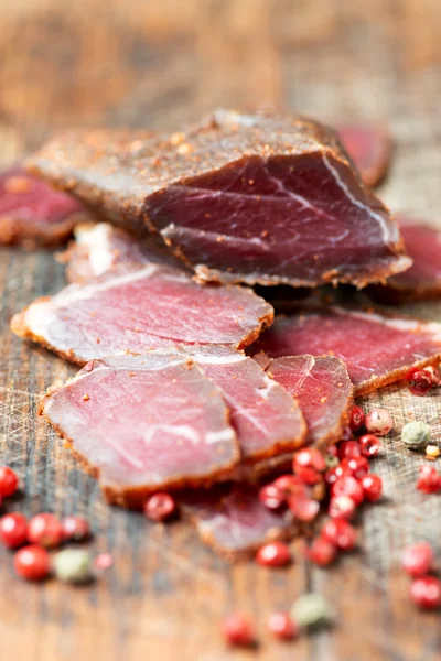 Slices of cured meet on wooden table — Stock Photo, Image