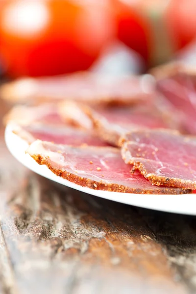 Slices of cured meet on plate vertical shallow depth of field — Stock Photo, Image