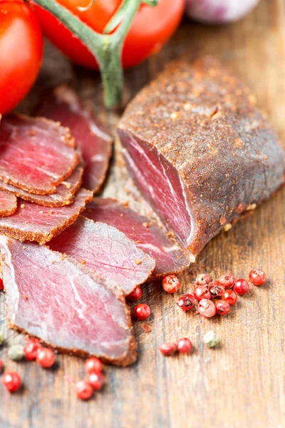 Slices of cured meet on wooden table close up — Stock Photo, Image