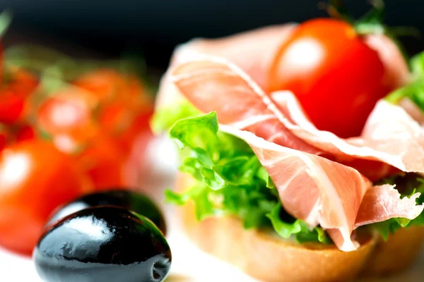 Sandwiches mit Prosciutto auf Teller mit Oliven — Stockfoto