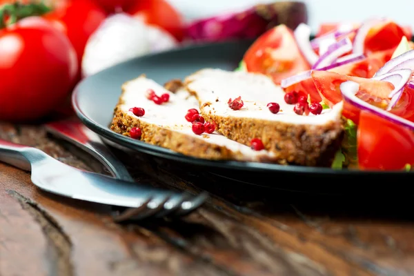 Carne di maiale al forno in piatto con insalata e ingredienti — Foto Stock