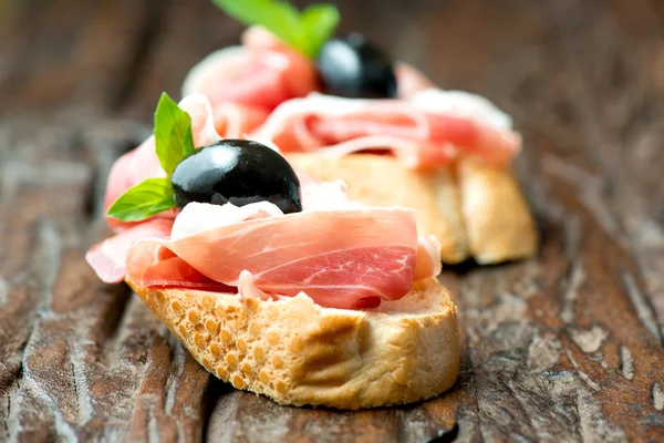 Sandwiches con jamón de oliva sobre mesa vieja de madera horizontal — Foto de Stock