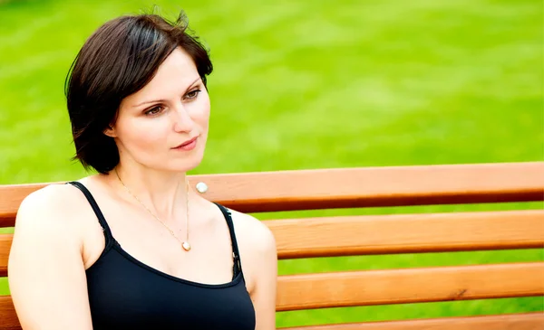 Portrait of brunette woman on bench — Stock Photo, Image