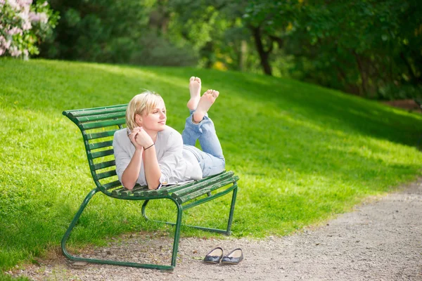 Молодая женщина лежит на скамейке — стоковое фото