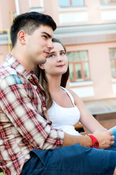 Young couple sitting on bench on street — Stock Photo, Image