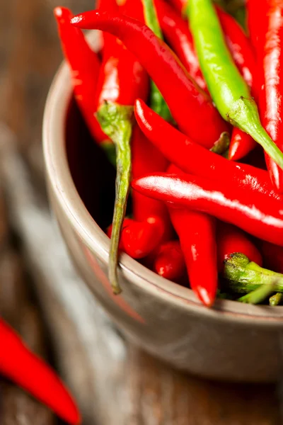 Chili peppers i skål på träbord — Stockfoto