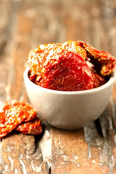 Italiaanse zon gedroogde tomaten in kom op houten tafel — Stockfoto