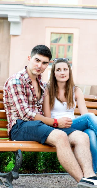 坐在长凳上大街上对年轻夫妇 — 图库照片