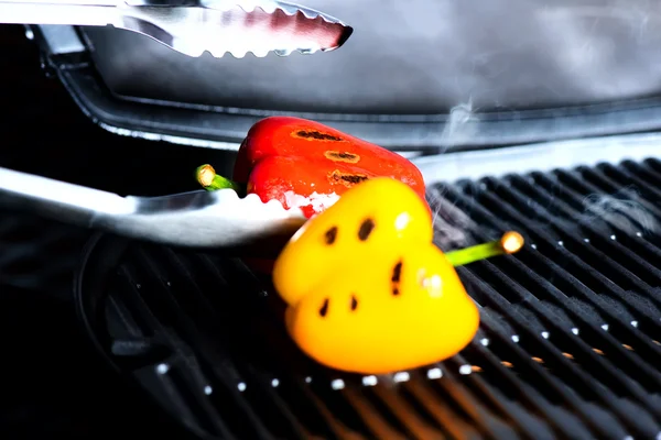 Bell peppers on a grill and tongs — Stock Photo, Image