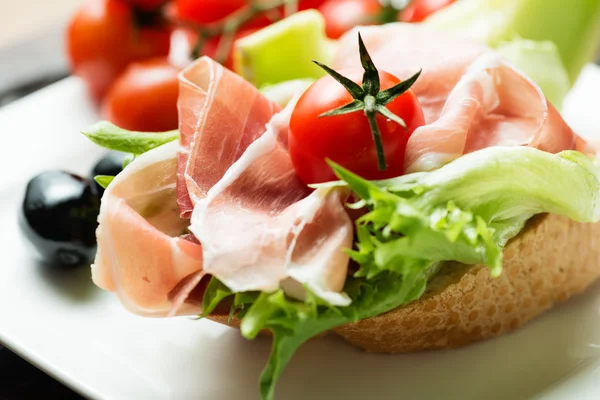 Ham sandwich with tomato and olive on plate — Stock Photo, Image