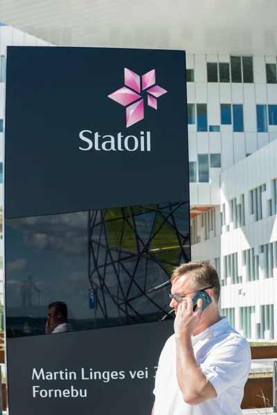 Человек звонит по телефону перед офисом Statoil — стоковое фото