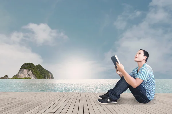 Mladý muž čte knihu na pláži — Stock fotografie