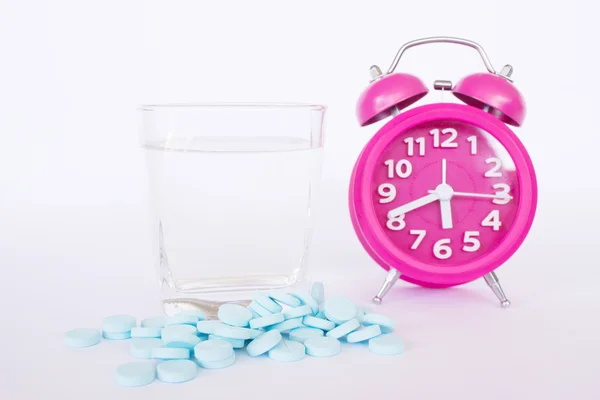 Comprimidos e relógio de alarme em fundo branco, conceito para médicos e cuidados de saúde — Fotografia de Stock