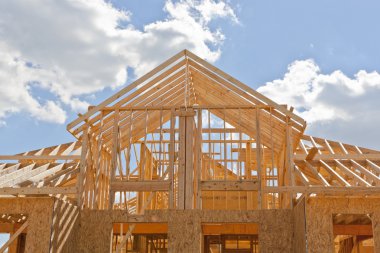 New residential construction home framing against a blue sky clipart