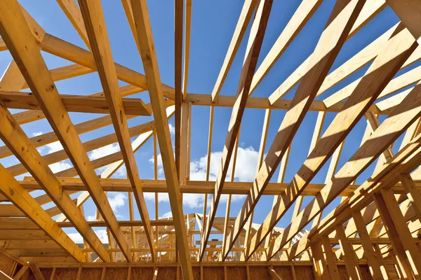 Nova casa de construção residencial enquadrando contra um céu azul — Fotografia de Stock