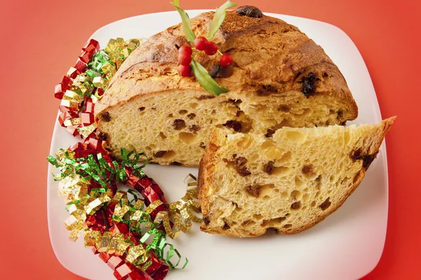 Panettone, a typical Christmas cake on a plate over a red backgr — Stock Photo, Image