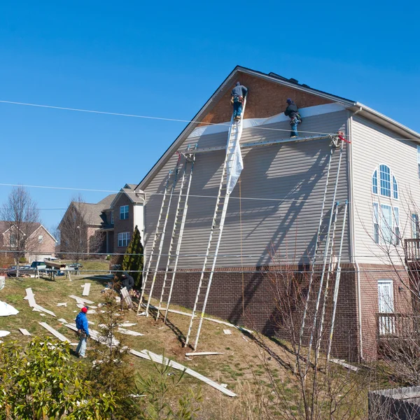 Workers installing plastic siding panels on two story house. — Stock Photo, Image