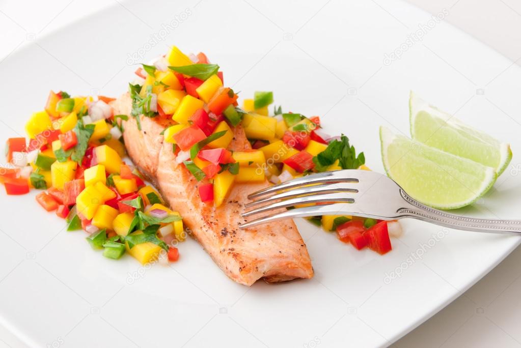 Salmon fillet with mango salsa on white plate.