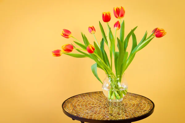 Tulipanes rojos en un jarrón sobre mesa de mosaico . —  Fotos de Stock