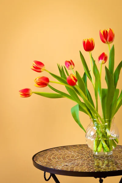 Tulipanes rojos en un jarrón sobre mesa de mosaico . —  Fotos de Stock