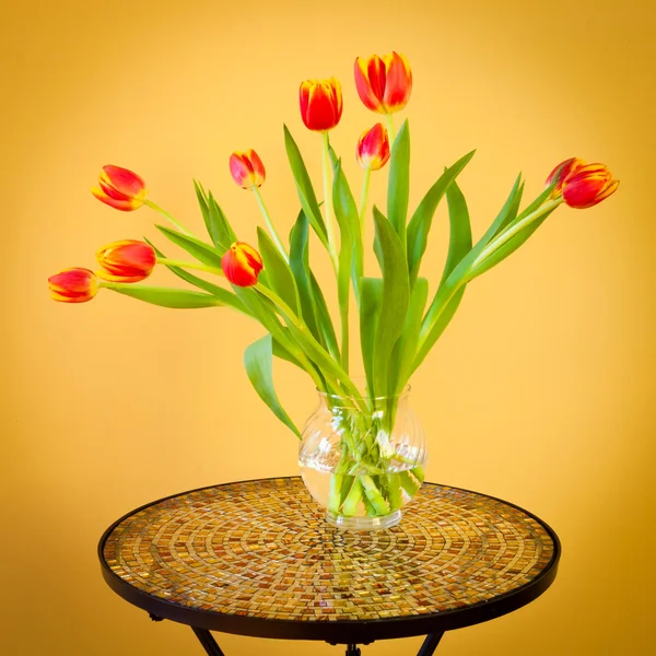 Tulipanes rojos en un jarrón sobre mesa de mosaico . —  Fotos de Stock