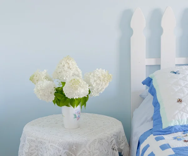 Buquê de flores de hortênsia brancas em uma mesa de cama do site em um sofá — Fotografia de Stock