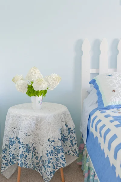 Bouquet of white hydrangea flowers on a side bed table in a coun — Stock Photo, Image