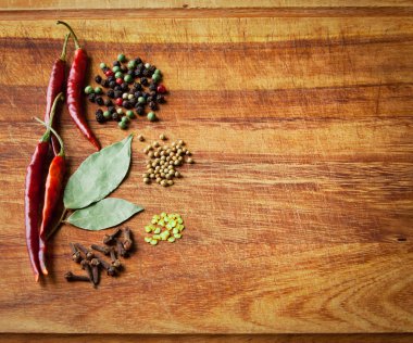 Dried red chili peppers and spiceson rustic, dark wood cutting board. clipart