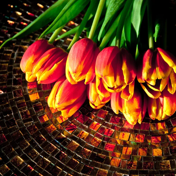 Röda tulpaner på mosaik bord. — Stockfoto