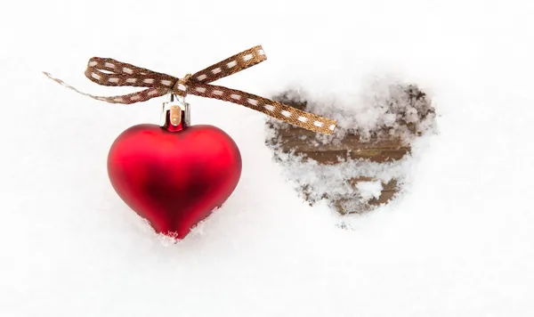 Red heart on snow next to melted heart shape — Stock Photo, Image