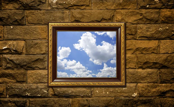 Uma foto de uma moldura de madeira na parede de tijolo com o céu no interior — Fotografia de Stock